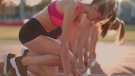 Tres-Mujeres-Jóvenes-En-El-Estadio-En-La-Línea-De-Salida-En-Bloques-Comienzan-La-Carrera-En-Cámara-Lenta